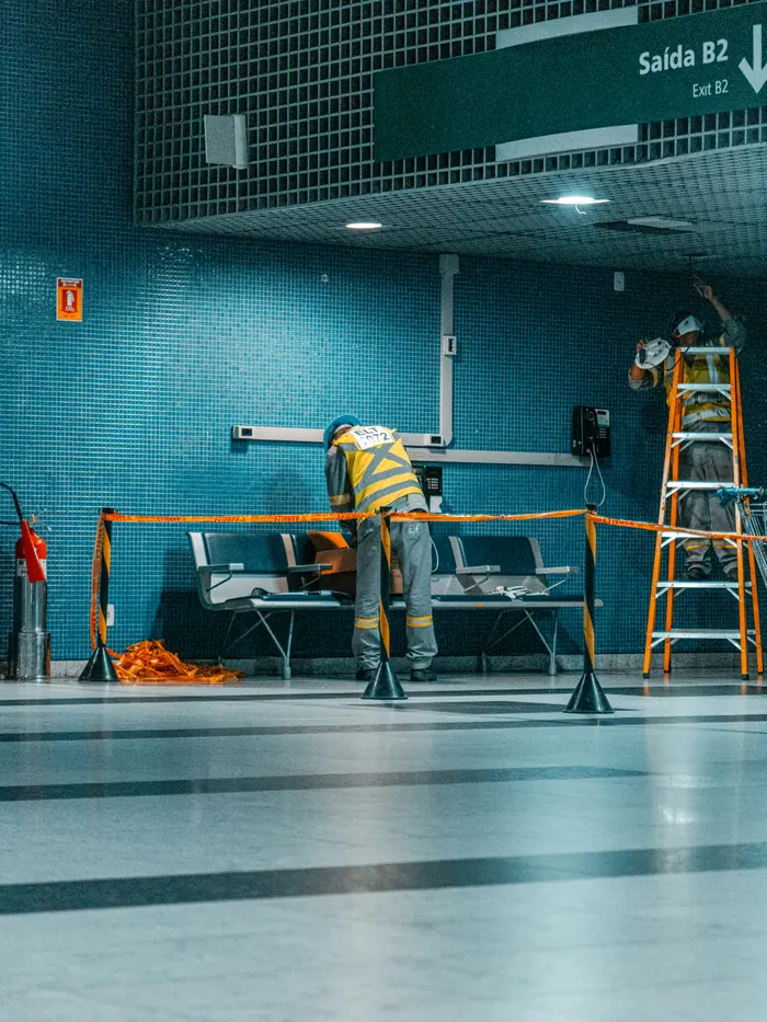 Maintenance crew with a ladder in a station concourse