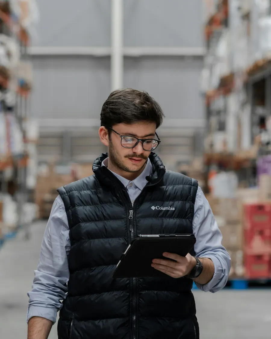 An operations supervisor with a tablet in a warehouse aisle
